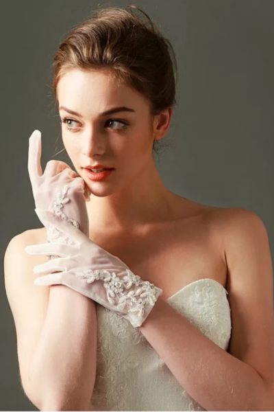 woman wearing a sleeveless bridal gown with short flower embellished gloves